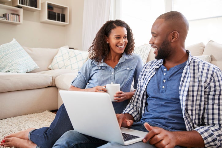 Young couple sitting on couch using a laptop
